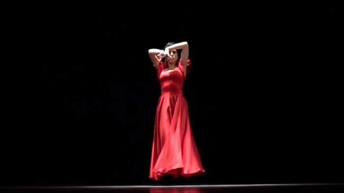 An attractive dancer in red chic costume is dancing flamenco.